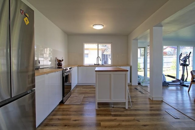 kitchen with tasteful backsplash, white cabinets, dark wood-type flooring, and appliances with stainless steel finishes