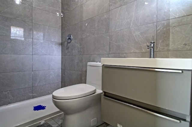 bathroom with vanity, toilet, tile walls, and walk in shower