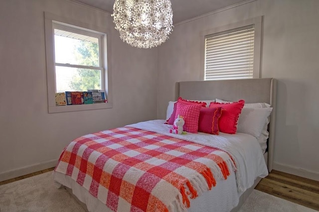 bedroom with hardwood / wood-style flooring, an inviting chandelier, and ornamental molding