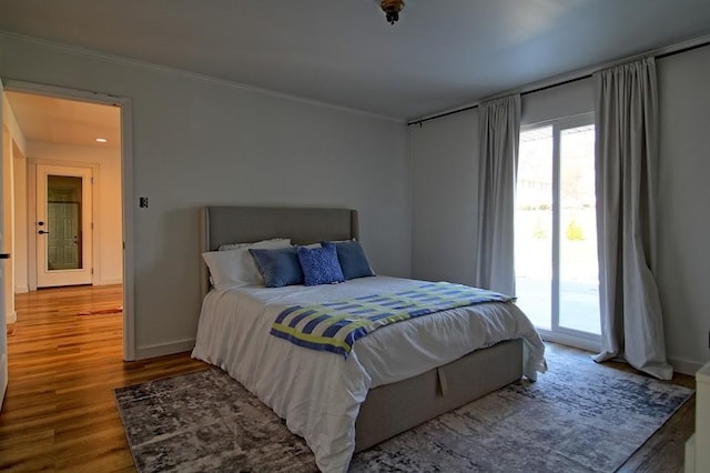 bedroom featuring access to outside, hardwood / wood-style flooring, and ornamental molding