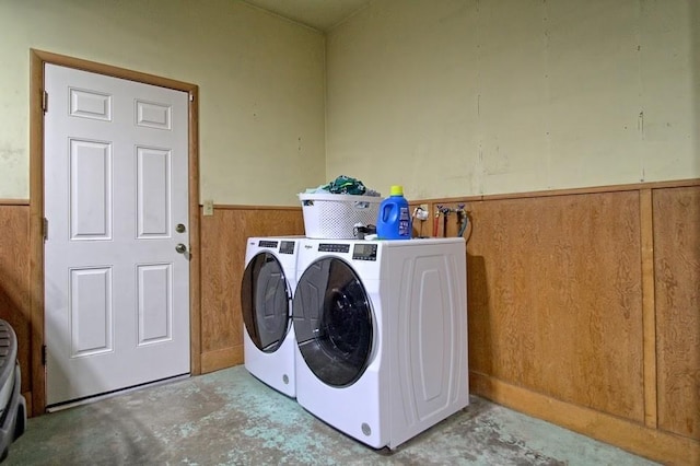 laundry room with washer and dryer and wood walls