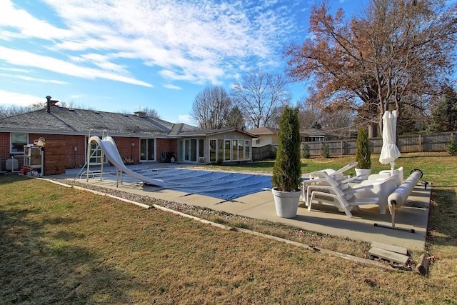 view of pool with a sunroom, a yard, a patio, and a water slide