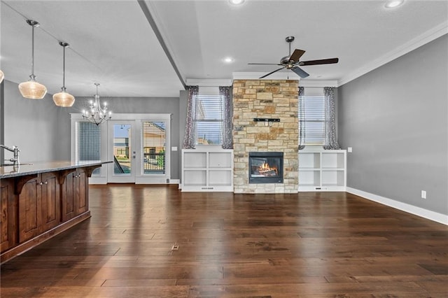 living room featuring a stone fireplace, crown molding, ceiling fan with notable chandelier, and dark hardwood / wood-style floors