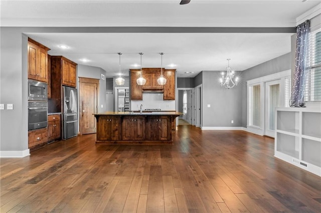 kitchen with a kitchen breakfast bar, hanging light fixtures, dark hardwood / wood-style floors, an island with sink, and stainless steel appliances