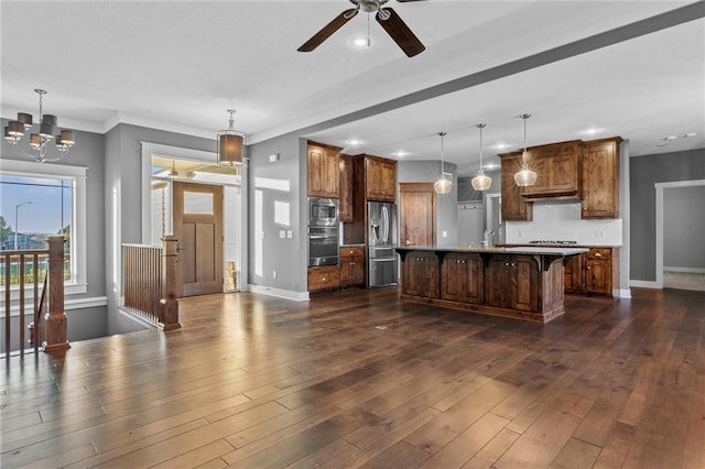 kitchen with a breakfast bar, an island with sink, decorative light fixtures, and appliances with stainless steel finishes