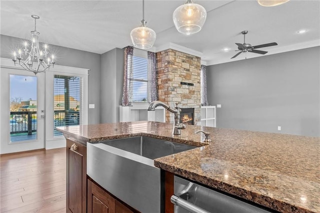 kitchen featuring wood-type flooring, ceiling fan with notable chandelier, hanging light fixtures, and ornamental molding