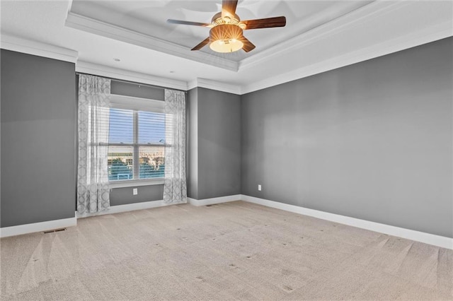 empty room featuring ceiling fan, a raised ceiling, ornamental molding, and light carpet