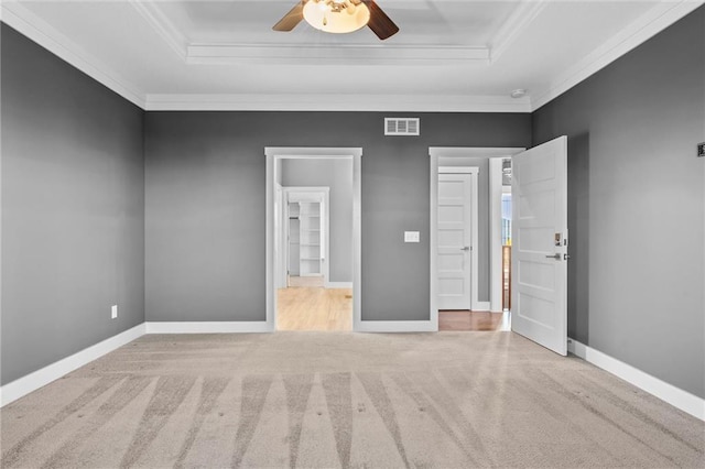 unfurnished bedroom with carpet flooring, a raised ceiling, ceiling fan, and crown molding