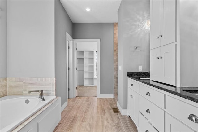 bathroom with wood-type flooring, vanity, and a bathing tub