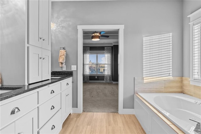 bathroom with ceiling fan, vanity, and a bath