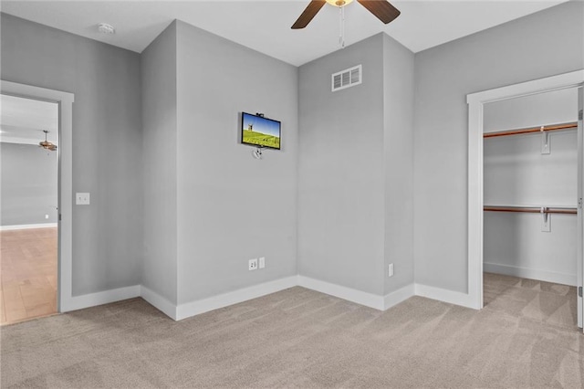 unfurnished bedroom featuring ceiling fan, light colored carpet, and a closet