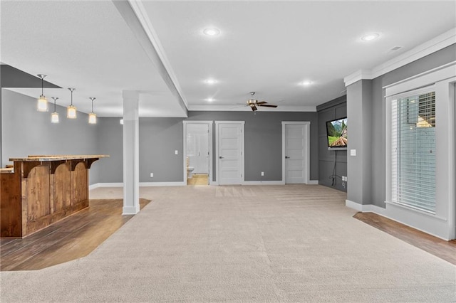 basement featuring ceiling fan, light wood-type flooring, and crown molding