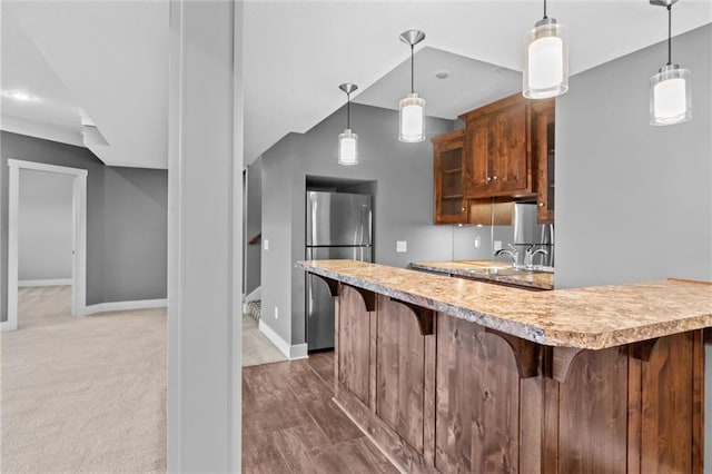 kitchen featuring stainless steel fridge, dark carpet, sink, pendant lighting, and a breakfast bar area