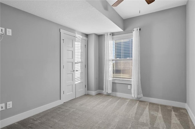 spare room with a textured ceiling, ceiling fan, and light carpet