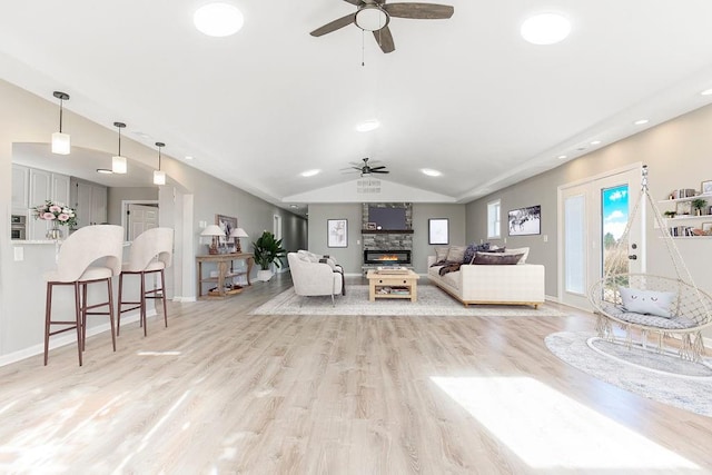 living room with a fireplace, lofted ceiling, light wood-style flooring, a ceiling fan, and baseboards