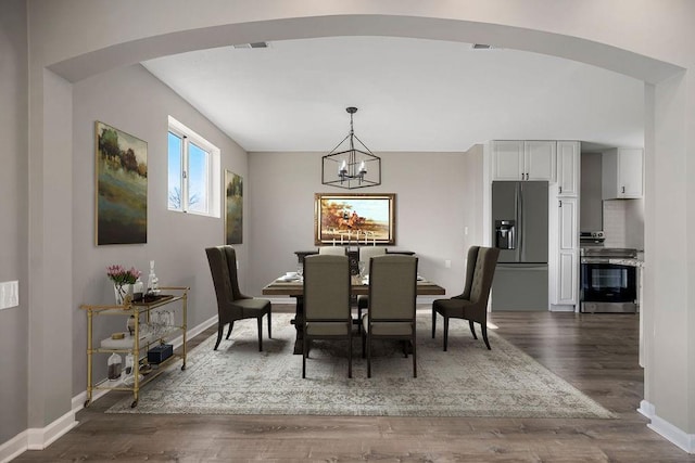 dining space featuring arched walkways, dark wood finished floors, visible vents, an inviting chandelier, and baseboards