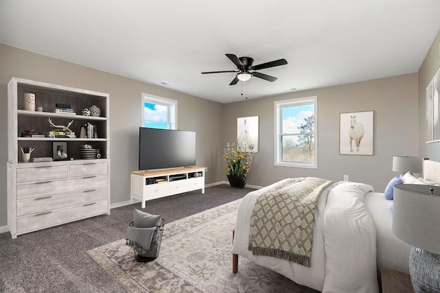 bedroom featuring multiple windows, dark carpet, a ceiling fan, and baseboards