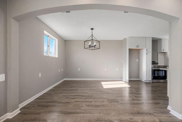 unfurnished dining area with dark wood-style floors, arched walkways, visible vents, an inviting chandelier, and baseboards