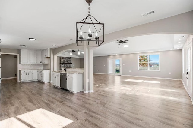 kitchen with arched walkways, open floor plan, light wood-type flooring, dishwasher, and ceiling fan with notable chandelier