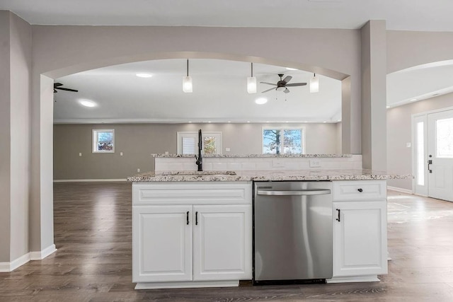 kitchen with plenty of natural light, arched walkways, a ceiling fan, dishwasher, and a sink