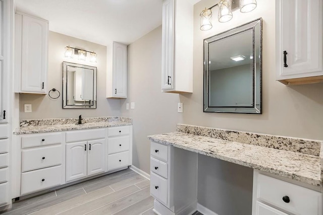 bathroom with wood finish floors, vanity, and baseboards