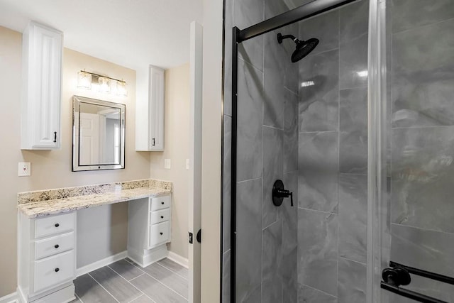 full bathroom with a shower stall, baseboards, and vanity