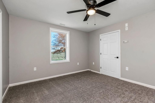 empty room featuring baseboards, visible vents, dark carpet, and ceiling fan