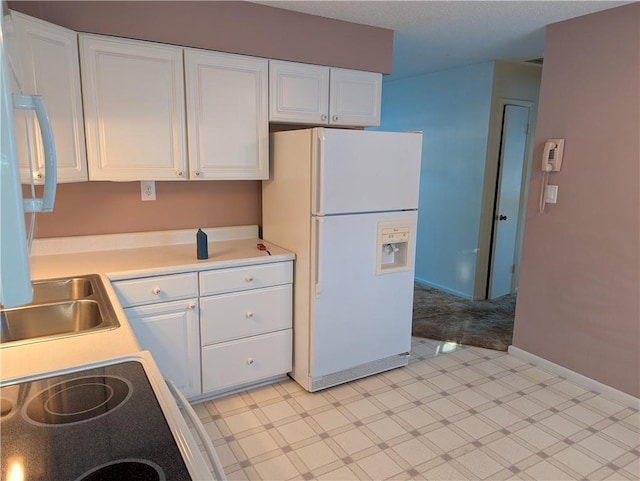 kitchen featuring white cabinetry, white fridge with ice dispenser, and range