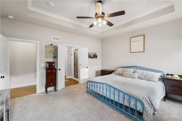 carpeted bedroom with a raised ceiling, ceiling fan, and crown molding