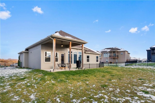 snow covered house with a patio area, ceiling fan, and a yard