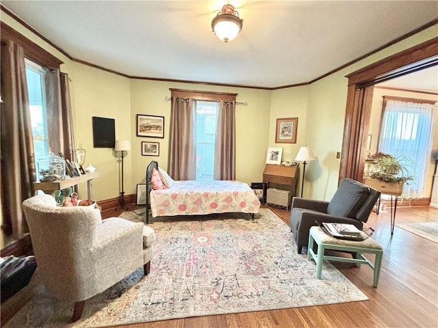 bedroom featuring ornamental molding, wood-type flooring, and multiple windows