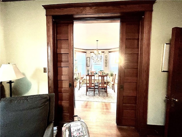 hallway with hardwood / wood-style flooring and a notable chandelier