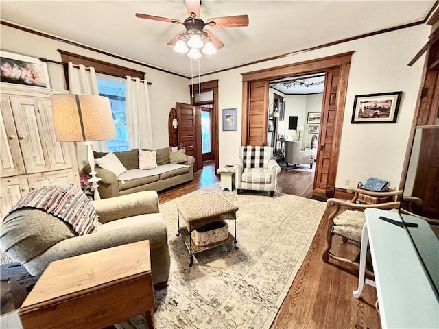 living room featuring dark wood-type flooring, ceiling fan, and crown molding