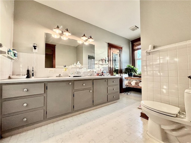 bathroom with tile walls, vanity, and toilet