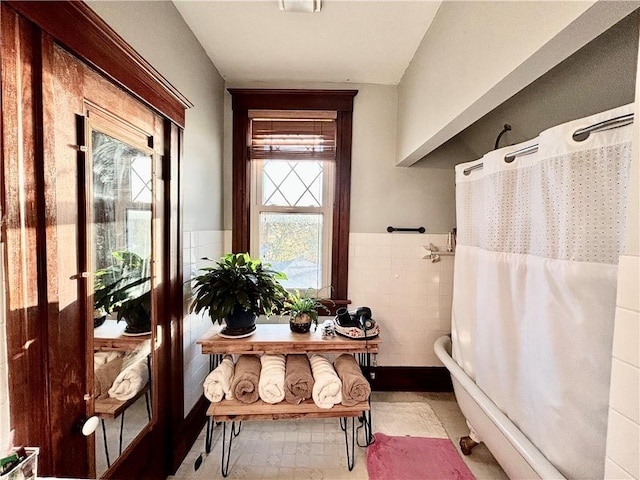 interior space with a bathtub, a wealth of natural light, and tile walls