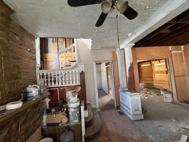 miscellaneous room featuring decorative columns, ceiling fan, and a textured ceiling