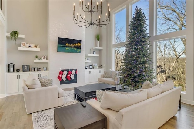 living room featuring light hardwood / wood-style floors, a chandelier, a healthy amount of sunlight, and a high ceiling