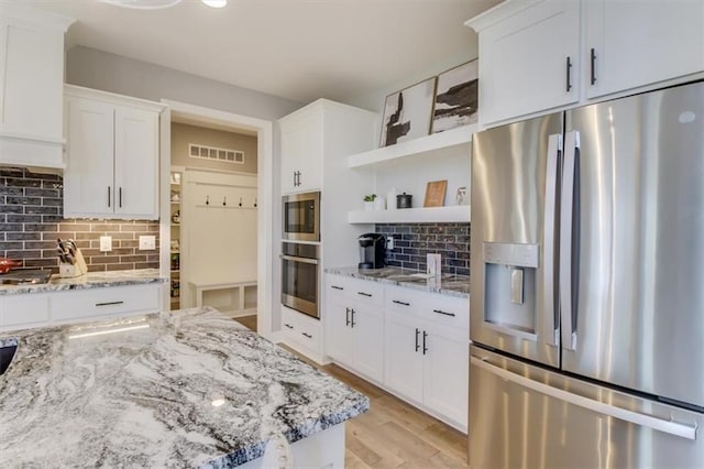 kitchen with white cabinetry, light stone counters, tasteful backsplash, and stainless steel appliances