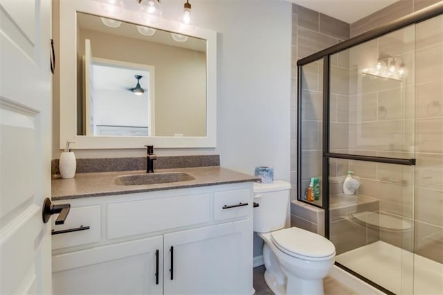 bathroom with vanity, a shower with door, and toilet