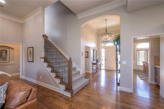 entrance foyer featuring hardwood / wood-style flooring, a towering ceiling, and crown molding