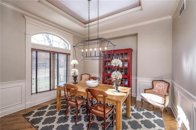 dining room with dark hardwood / wood-style flooring, a raised ceiling, crown molding, and a notable chandelier