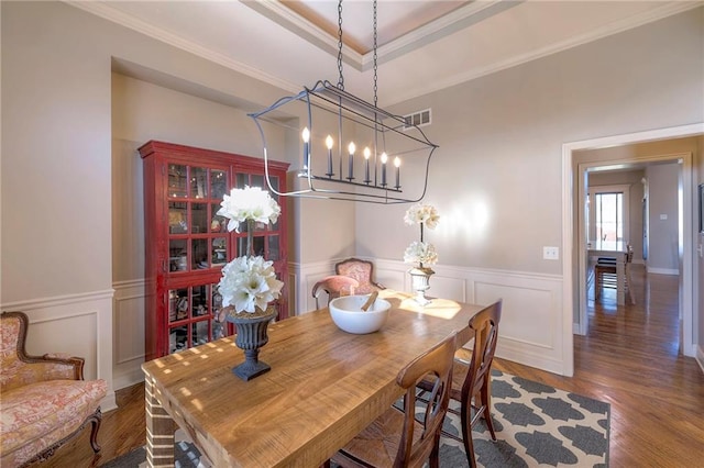 dining room featuring a raised ceiling, crown molding, wood-type flooring, and a notable chandelier