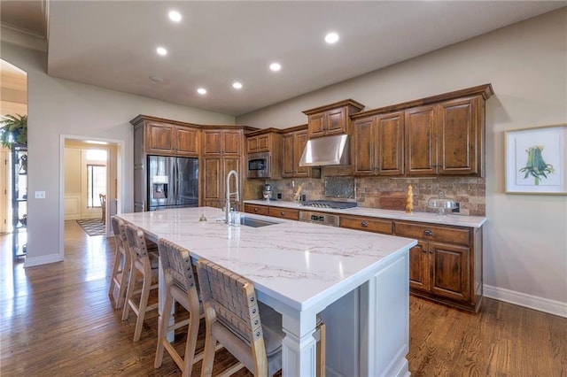 kitchen with a kitchen bar, appliances with stainless steel finishes, a kitchen island with sink, and sink