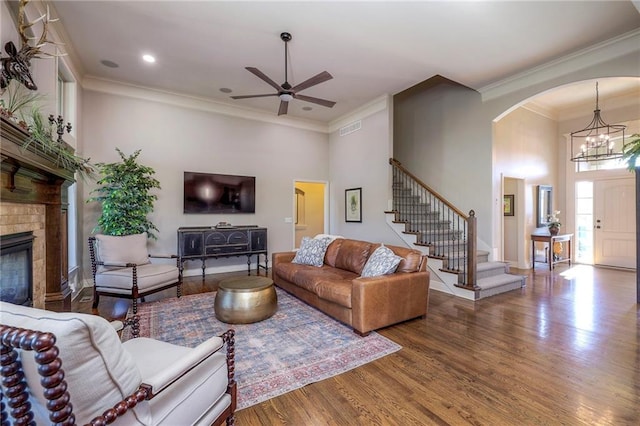 living room with wood-type flooring, ceiling fan with notable chandelier, and crown molding