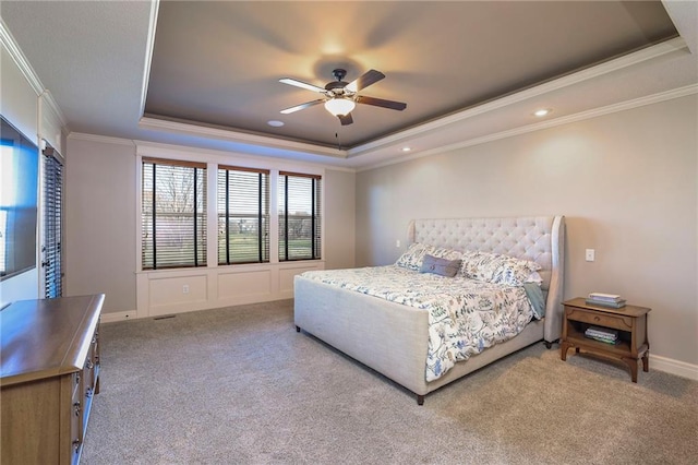 carpeted bedroom with a tray ceiling, ceiling fan, and ornamental molding