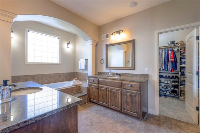 bathroom with tile patterned flooring, vanity, tiled bath, and ornate columns