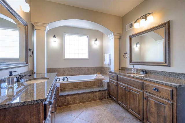 bathroom with tile patterned floors, vanity, tiled bath, and decorative columns