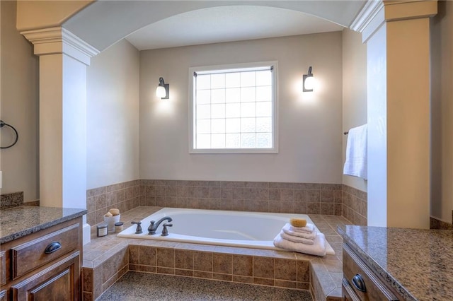 bathroom with vanity, a relaxing tiled tub, and ornate columns