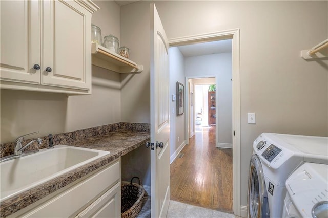 clothes washing area with cabinets, independent washer and dryer, and sink