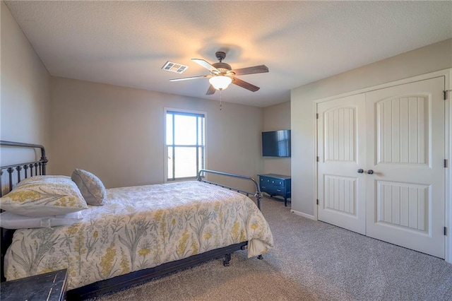 carpeted bedroom featuring a textured ceiling, a closet, and ceiling fan